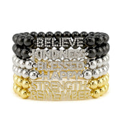 Stack of gold and silver beaded bracelets with motivational words on a white background