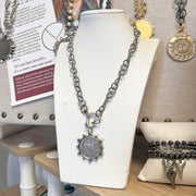 Necklace with a pendant on a white mannequin bust in a store setting.