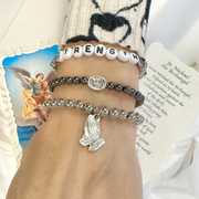 subliminal saint michael the archangel bracelet worn on model stacked with other bracelets love lisa