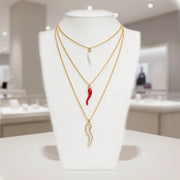 Tatiana Italian horn necklaces layered on a white jewelry display with gold chains and protection horn charms