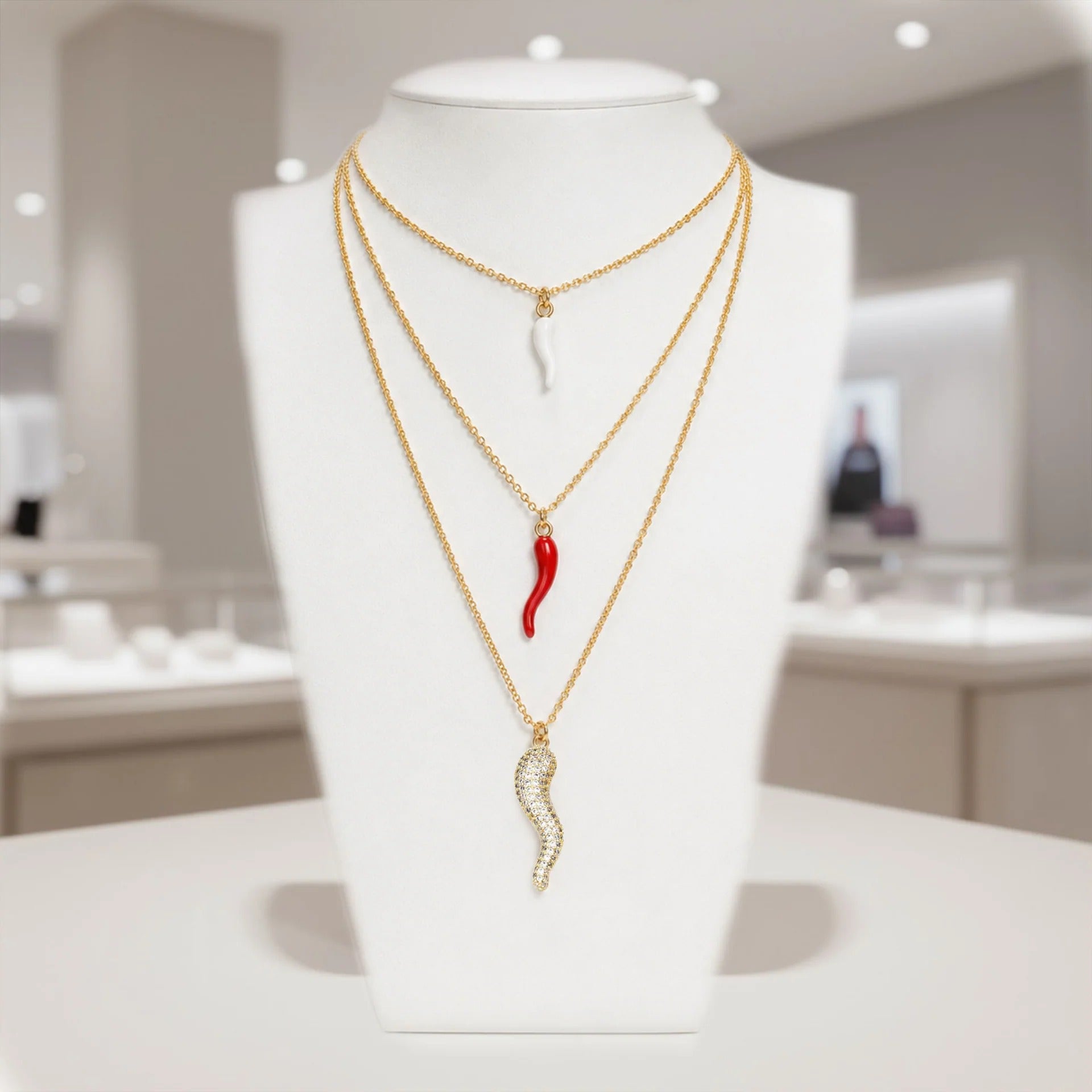 Tatiana Italian horn necklaces layered on a white jewelry display with gold chains and protection horn charms