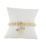 Mixed metal beaded bracelet with pavé crystal clasp designed for charm customization shown with bow charm on display pillow