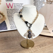 tina queen bee necklace on display stand gold and black