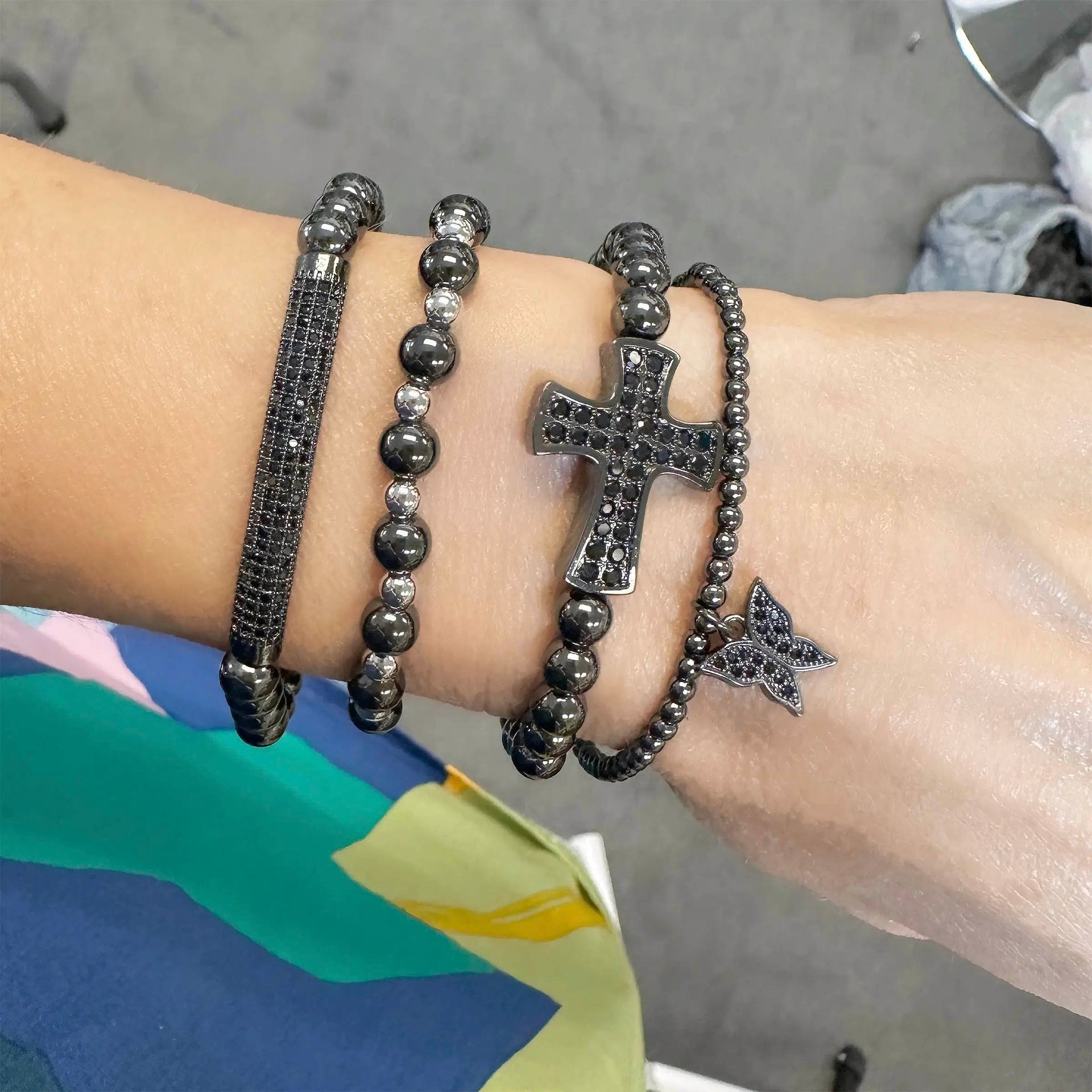Wrist wearing multiple black beaded bracelets with a star charm on a neutral background