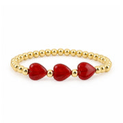 Triple Mini Heart Worry Stone Bracelet with three glossy red heart-shaped stones centered between polished gold-tone beads