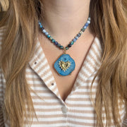 Necklace with a blue pendant featuring a heart design worn by a person with long hair.