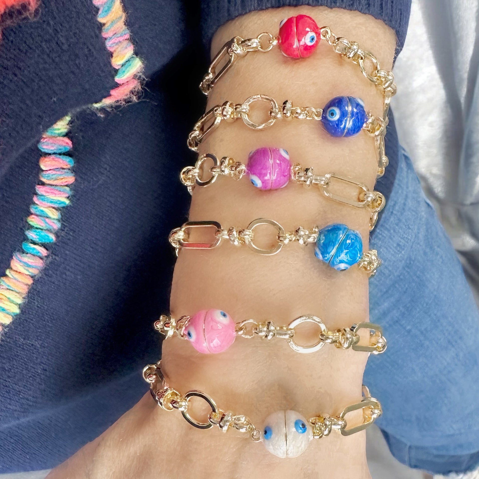 aleria evil eye magnetic chain link bracelet layered with gold bracelets on wrist