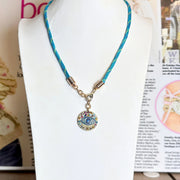 Vera coin charm on a paracord necklace