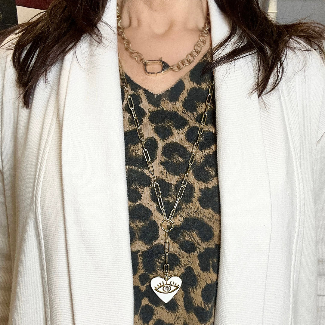 Person wearing a leopard print top with a necklace featuring a heart-shaped pendant.