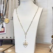 Necklace with a heart-shaped pendant on a mannequin bust in a store setting.