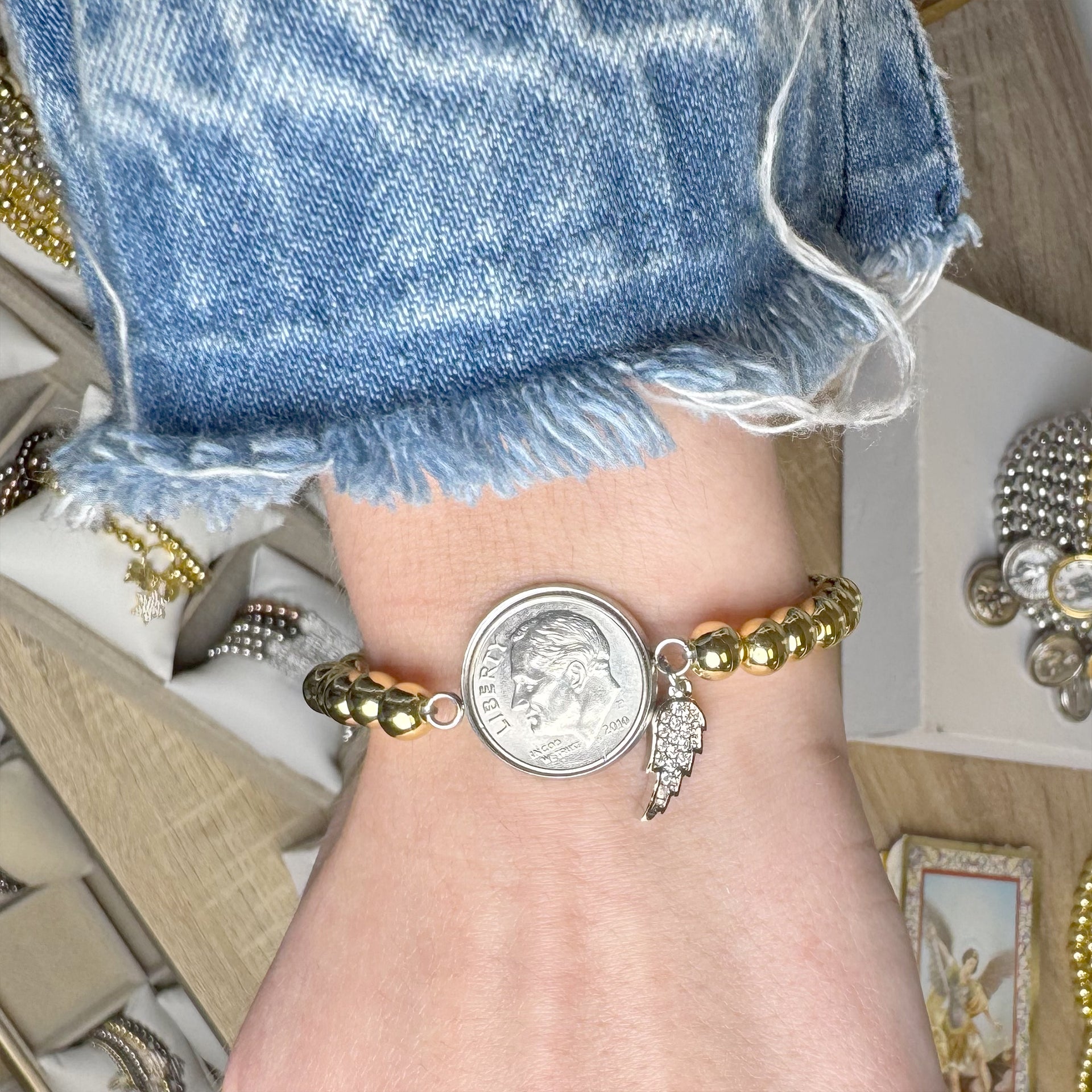 Close-up of a wrist wearing gold beaded bracelets with decorative charms.