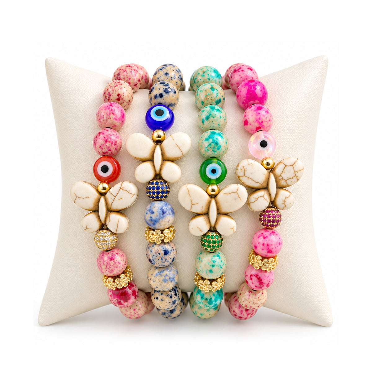 Love Lisa Wish & Wonder Butterfly Sea Sediment Jasper Bracelets displayed on a white pillow in Love, Dream, Luck, and Hope colorways