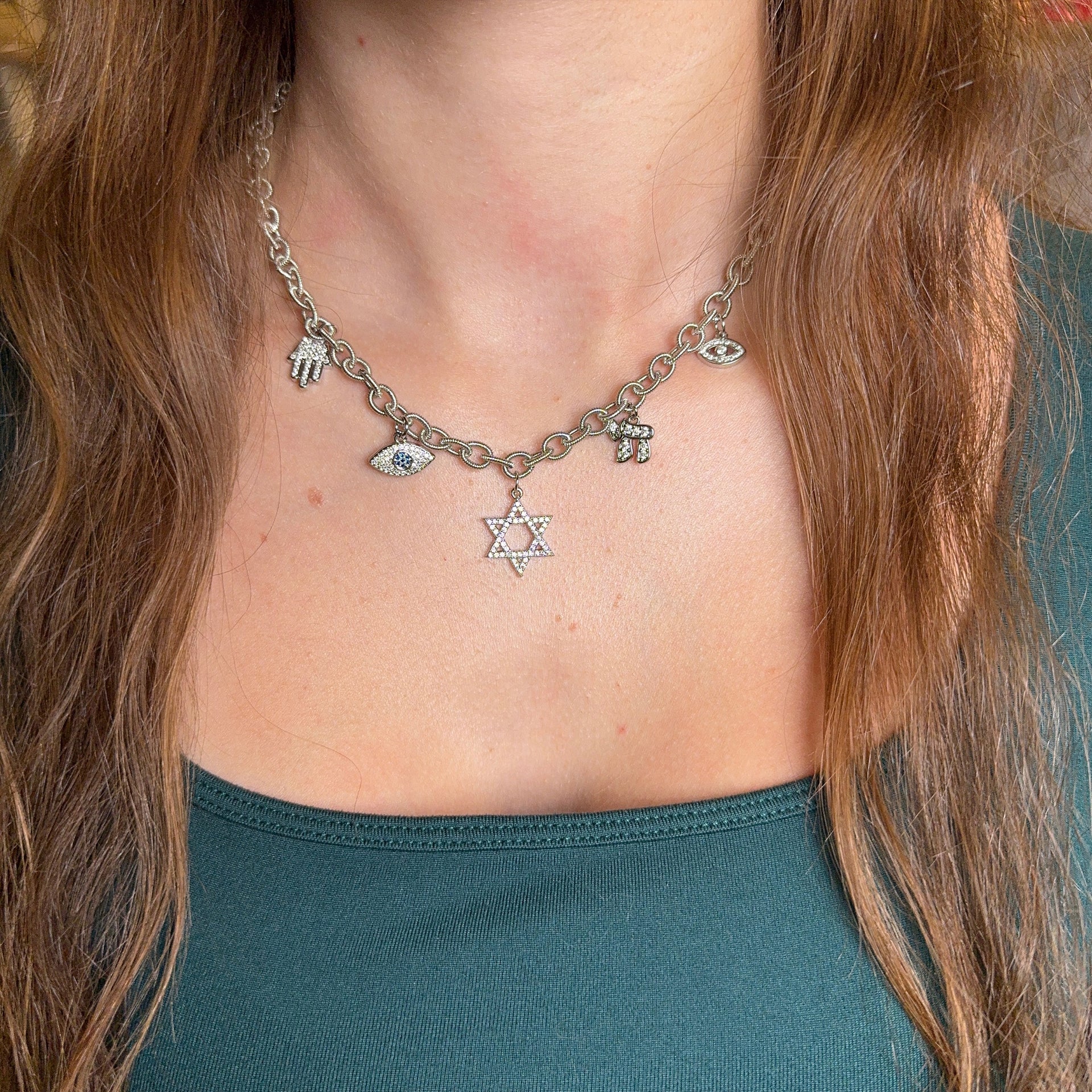 Necklace with various charms including a Star of David pendant worn by a person with long hair.