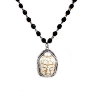 closeup of buddha pendant on black beaded necklace