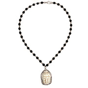 closeup of buddha pendant on black beaded necklace