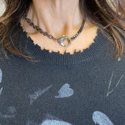 woman wearing gunmetal clasp necklace styled with graphic sweater