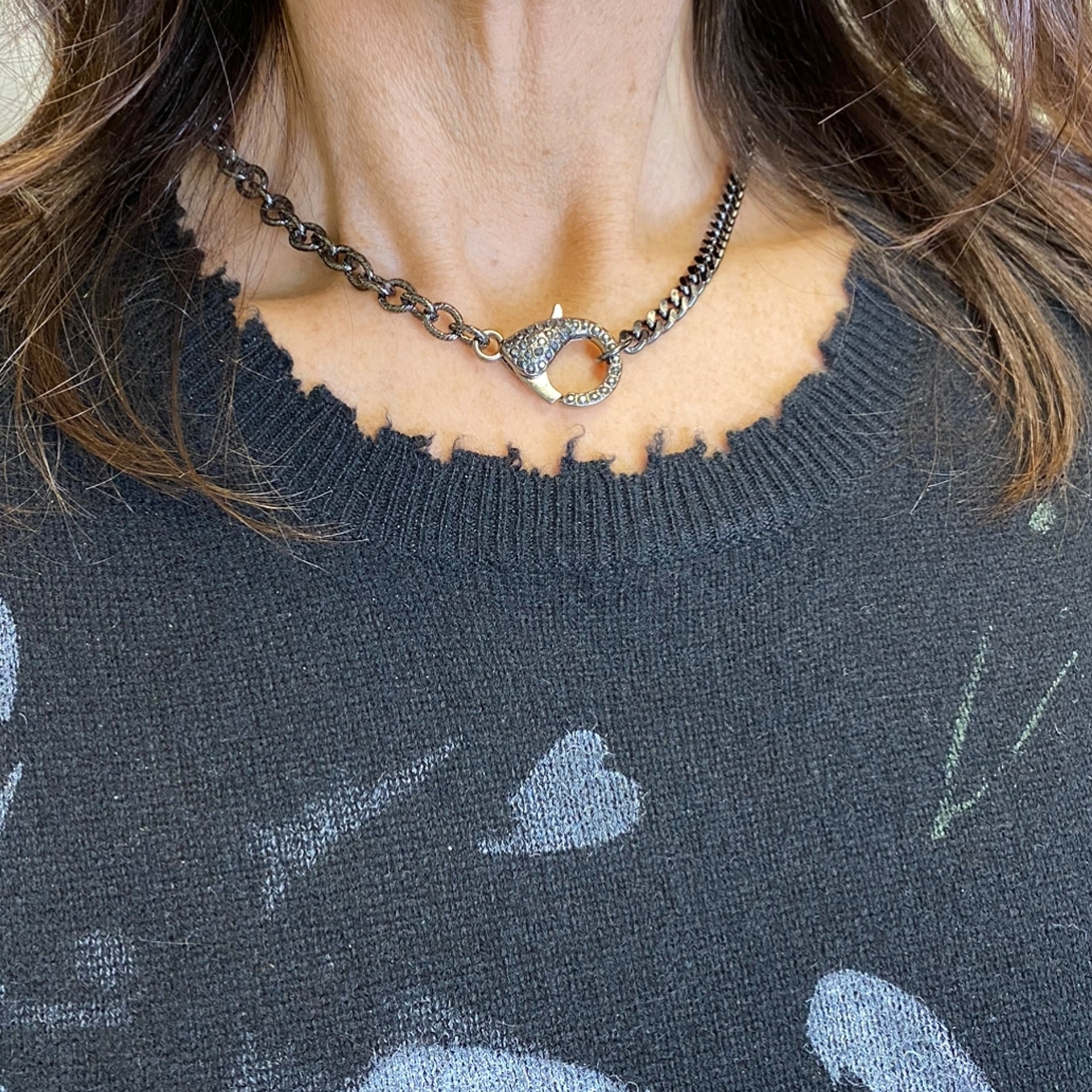 woman wearing gunmetal clasp necklace styled with graphic sweater