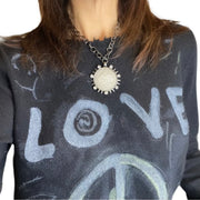 woman wearing LOVE coin necklace styled over graphic shirt showing detailed coin pendant