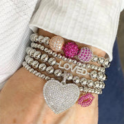 lila allure beaded heart bracelet in silver with smooth metallic beads and a radiant silver pave heart charm stacked on wriest with loved bracelet 