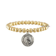 A gold-colored bracelet featuring a series of round beads and a central medal depicting St. Gerard, with a prayer card attached.