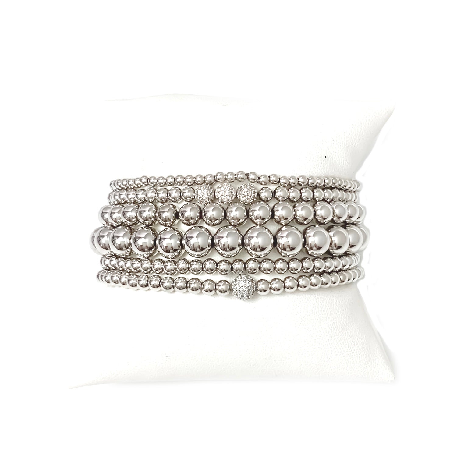 A series of six silver beaded bracelets stacked together, featuring a variety of round beads.