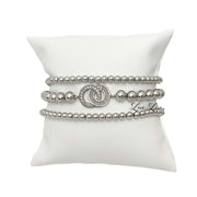 Love Lisa Together Forever silver beaded bracelet stack displayed on pillow with crystal baguette centerpiece bracelet